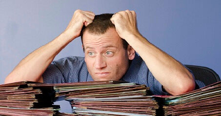 Stressed looking main leaning on a large stack of files at work