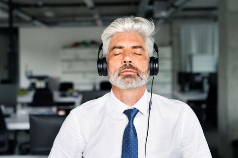 white haired man meditating with headset