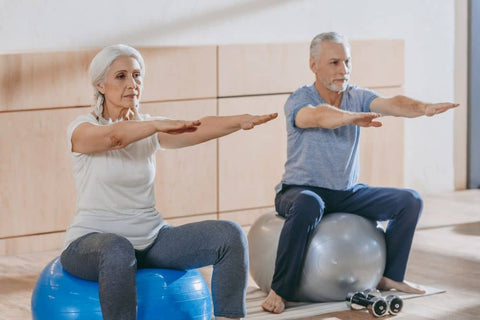 grey haired couple balancing on large rubber balls