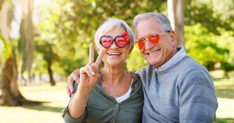 Grey haired couple outdoors with matching heart shaped sunglasses