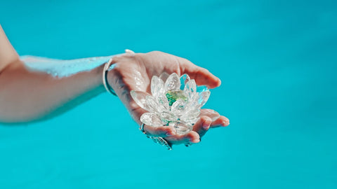 woman's hand against blue background holding fragile lotus blossom