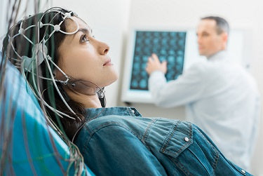 Woman in blue attached to brain monitor