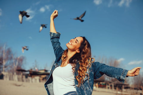 Smiling woman with outstretched arms enjoying mental balance