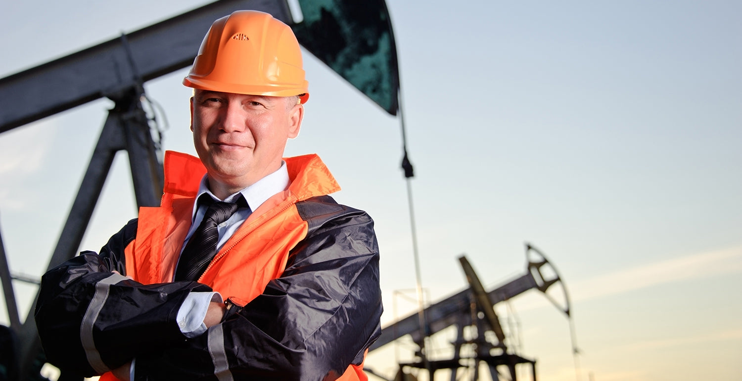 Photo of worker standing in front of an oil drill