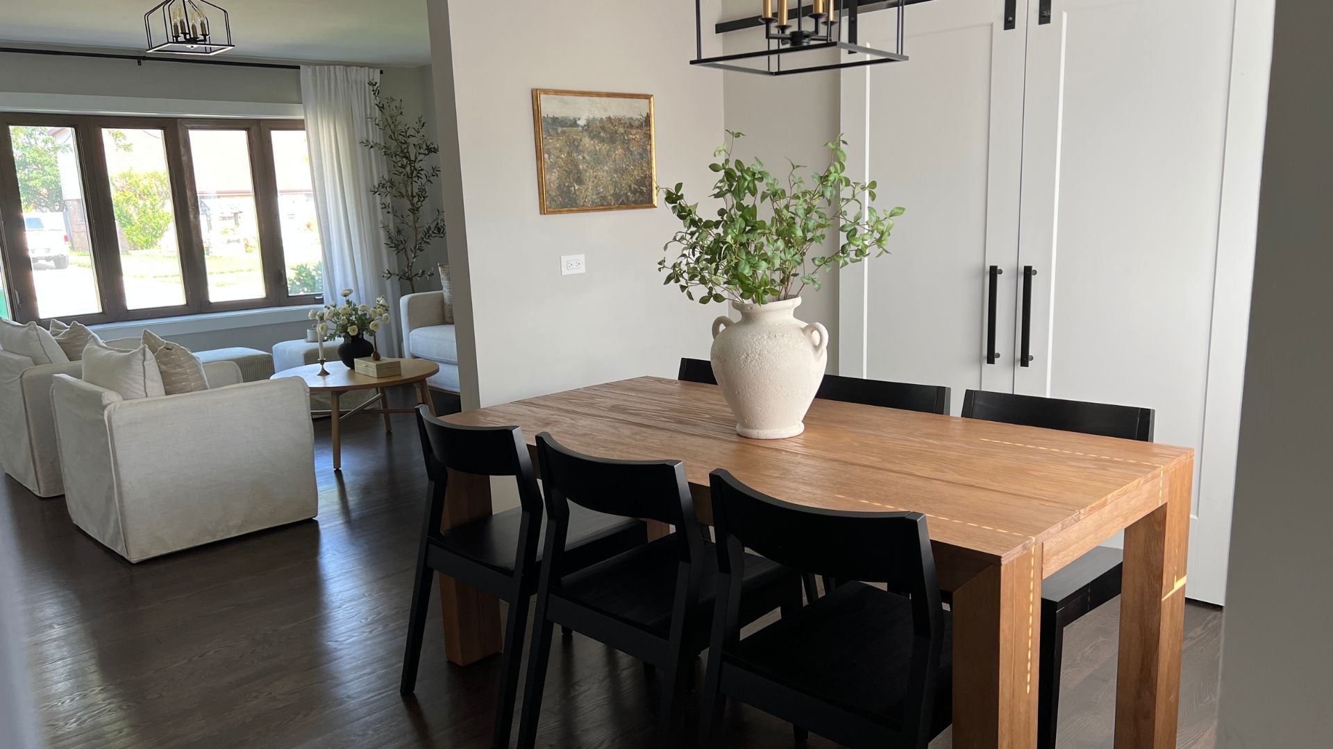 Black solid wood dining chairs with modern dining table in pecan, greenery and cream sofas