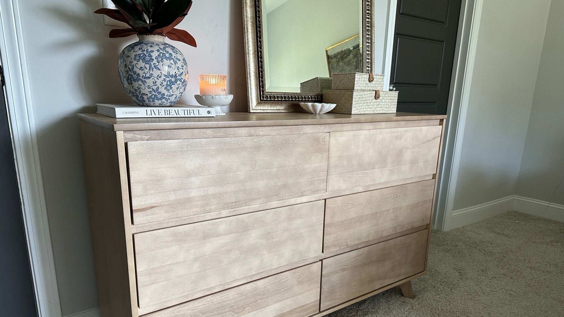 Modern 6-drawer dresser in blonde with mirror, book, vase, and candle