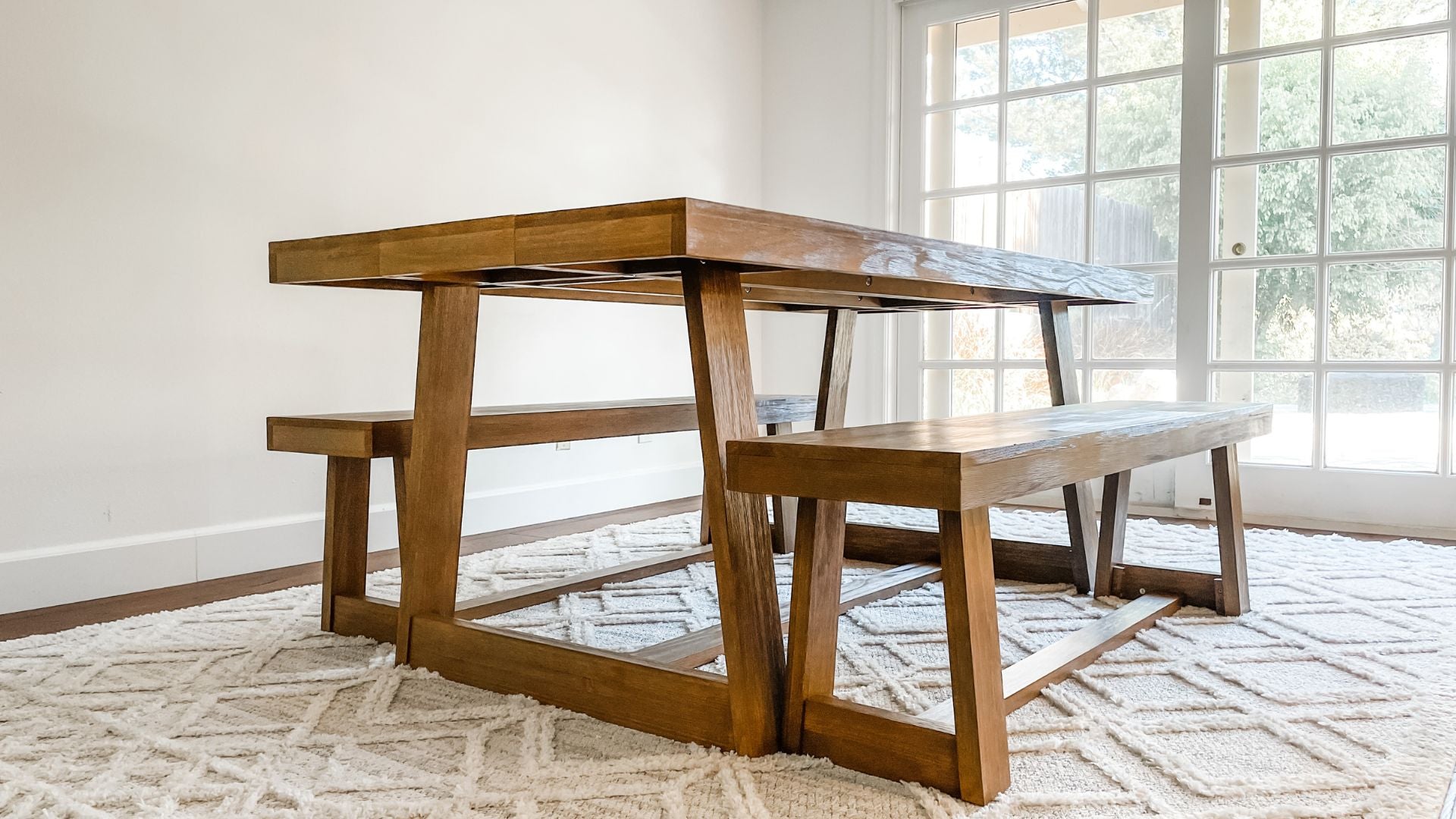Solid wood dining table set in pecan with two dining benches in pecan and woven rug