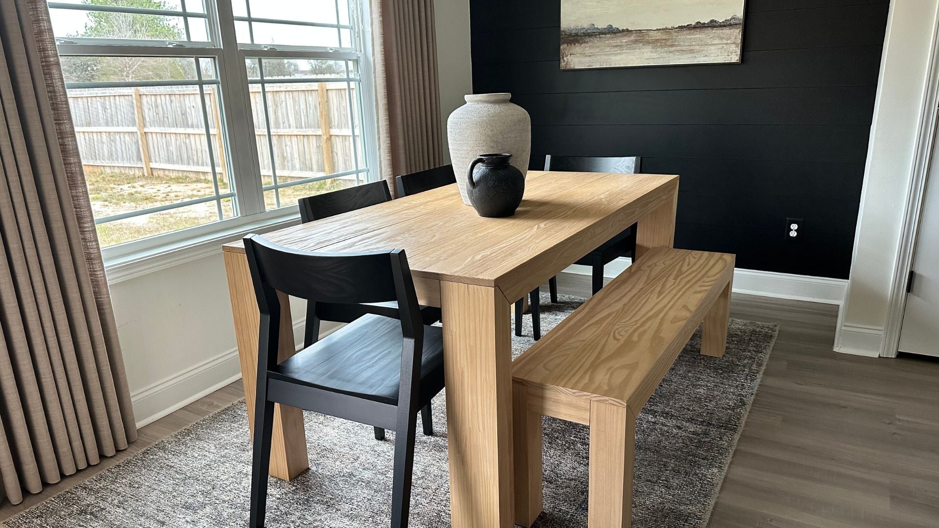 light wood dining table with dining bench and black dining chairs