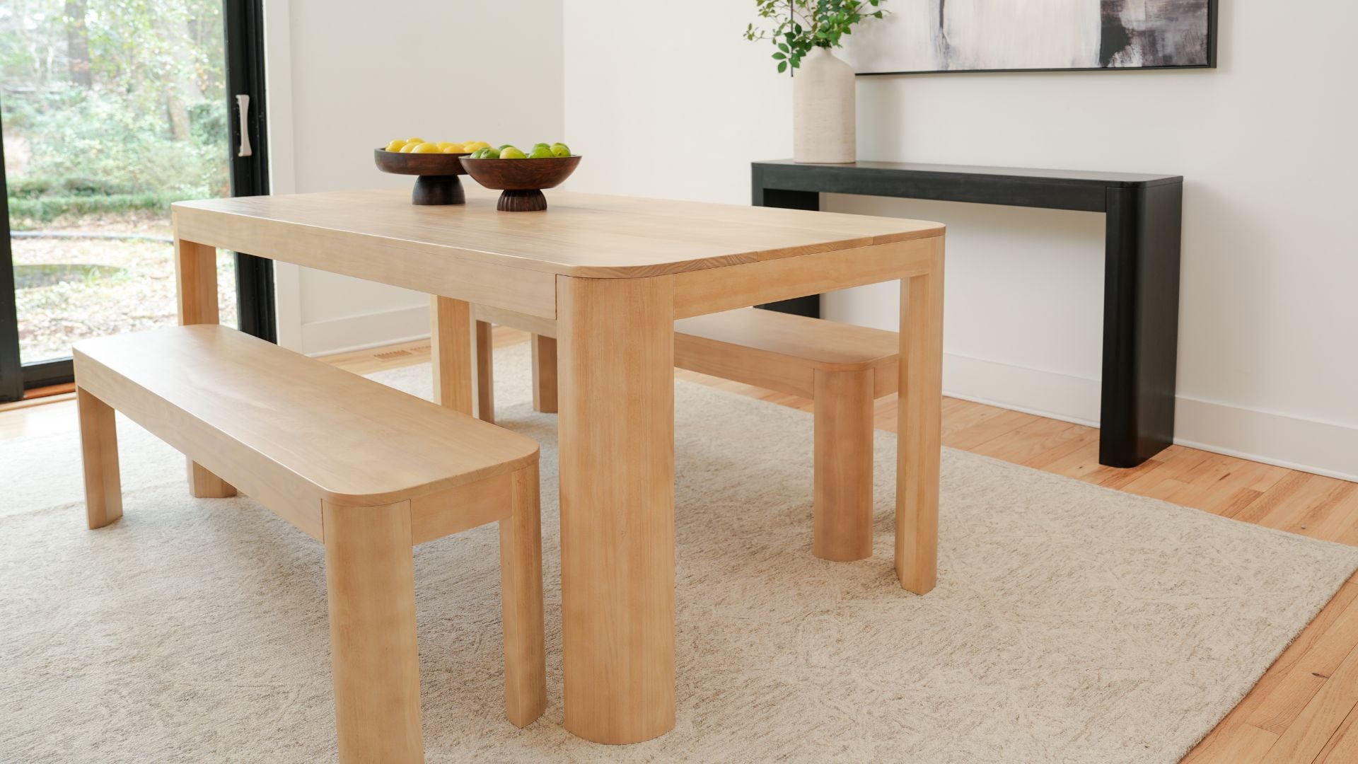 Natural wood dining table with two dining benches and black console table