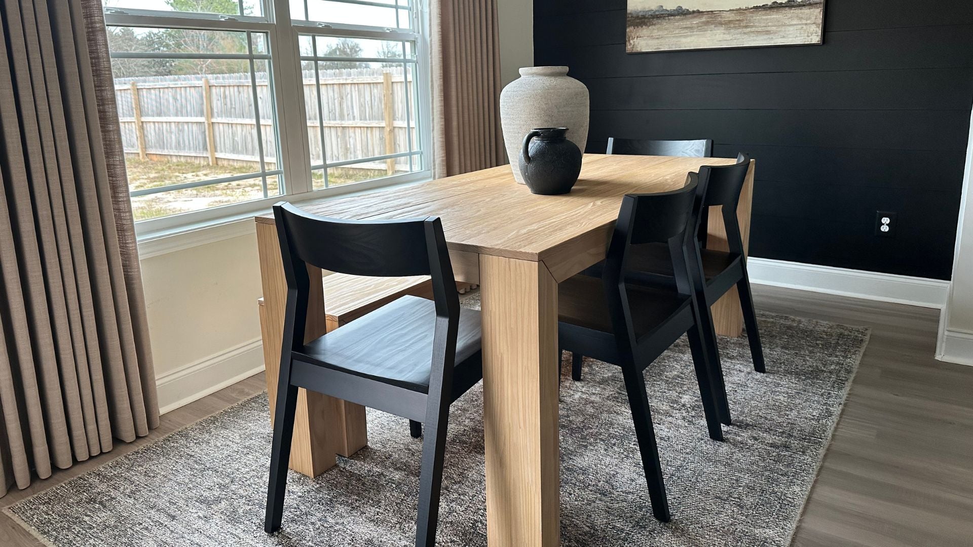 light solid wood dining room table with black dining chairs