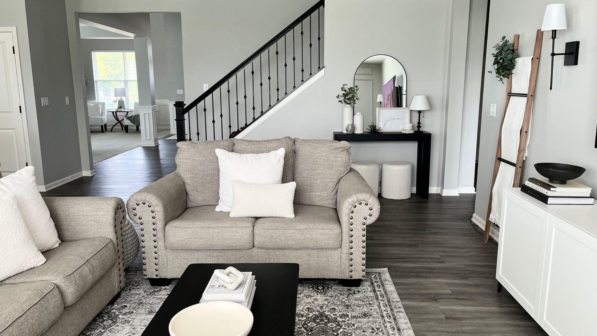 Modern living room with neutral colored sofas, solid wood black console table, and black coffee table