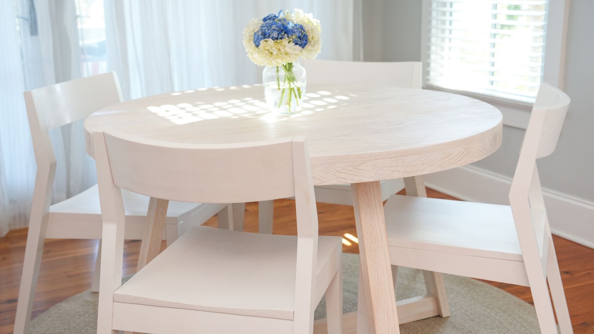 round wooden dining table with white dining chairs