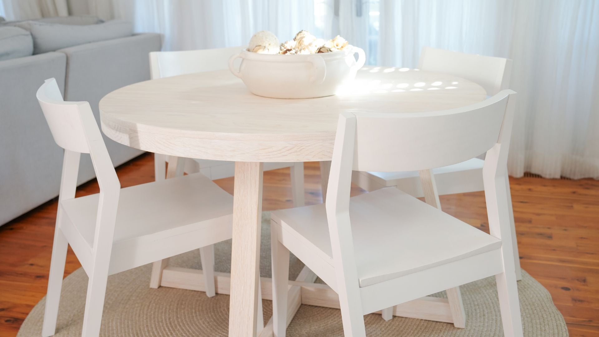 round wood dining table with white dining chairs