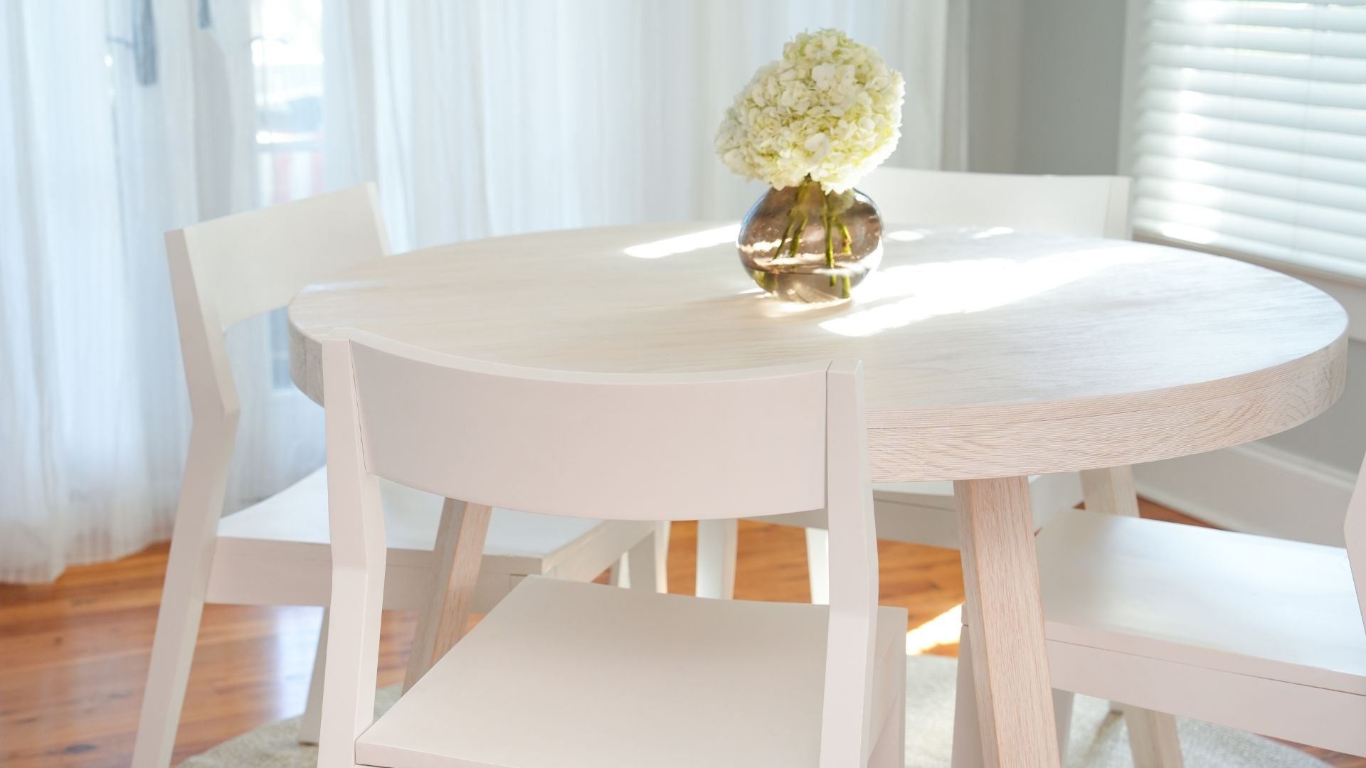 round wood dining table with white dining chairs