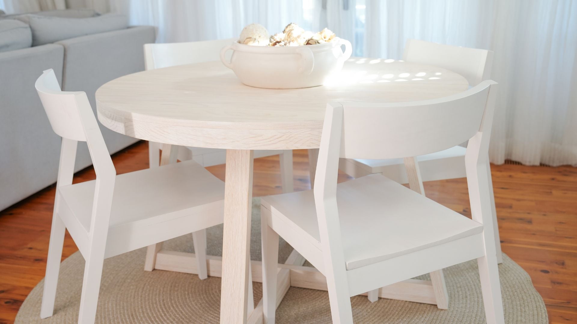 round wooden dining table in white sand wirebrush with white dining chairs