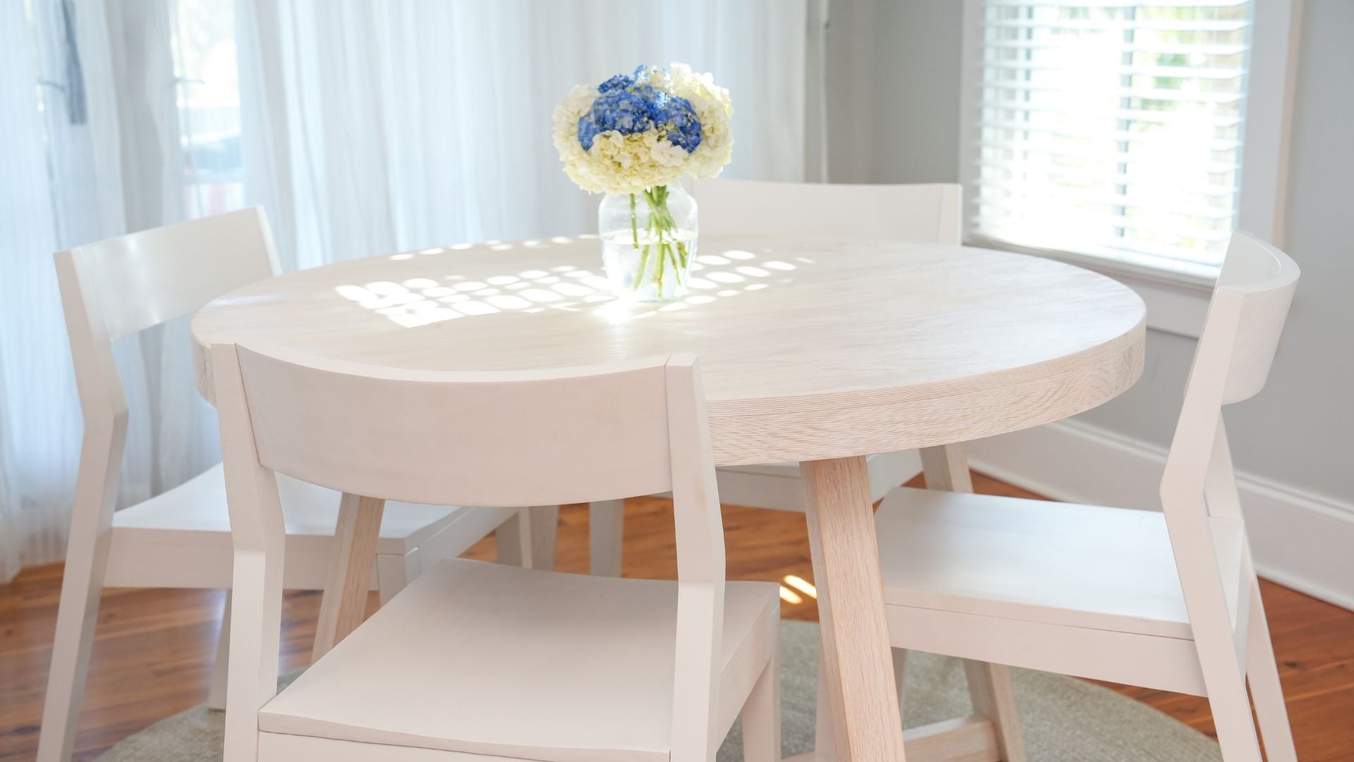 solid wood round dining table with white dining chairs