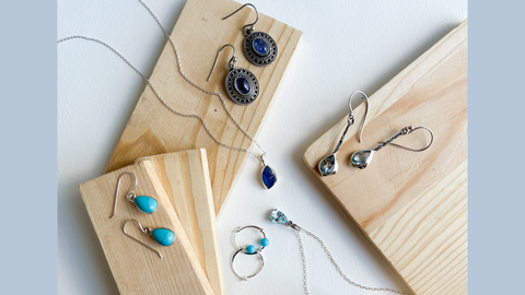 tanzanite, blue topaz and turquoise jewelry on wood display on white background