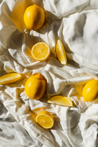 Limones y trozos de limón iluminados por luz natural sobre un paño blanco