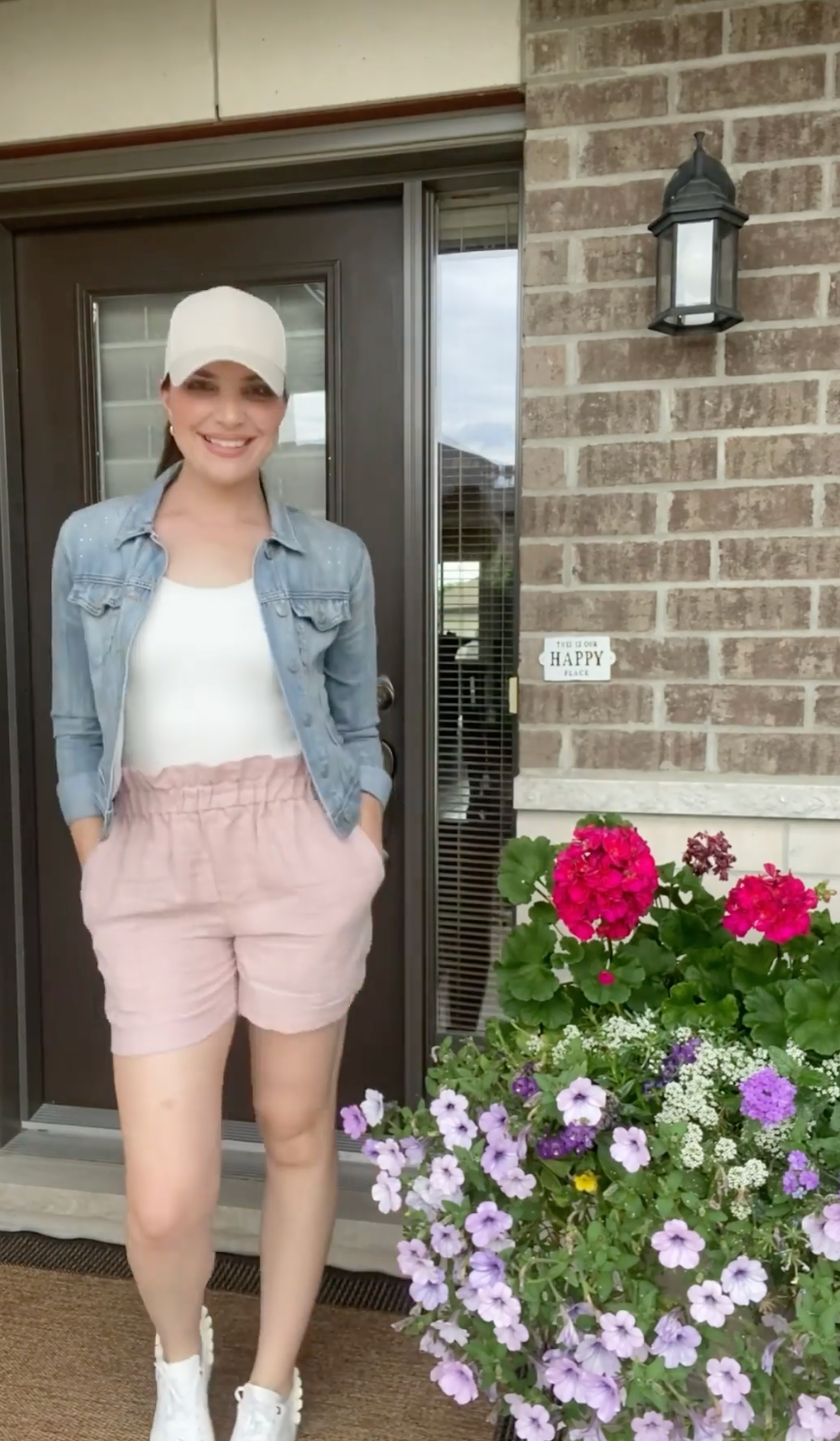 woman wearing jean jacket, pink shorts, and white bodysuit