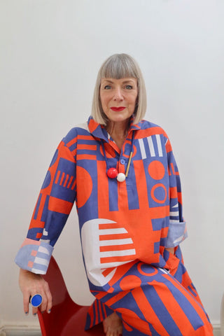 photo of model with a sharp grey bob wearing a red white and blue nightshirt and matching statement jewellery 