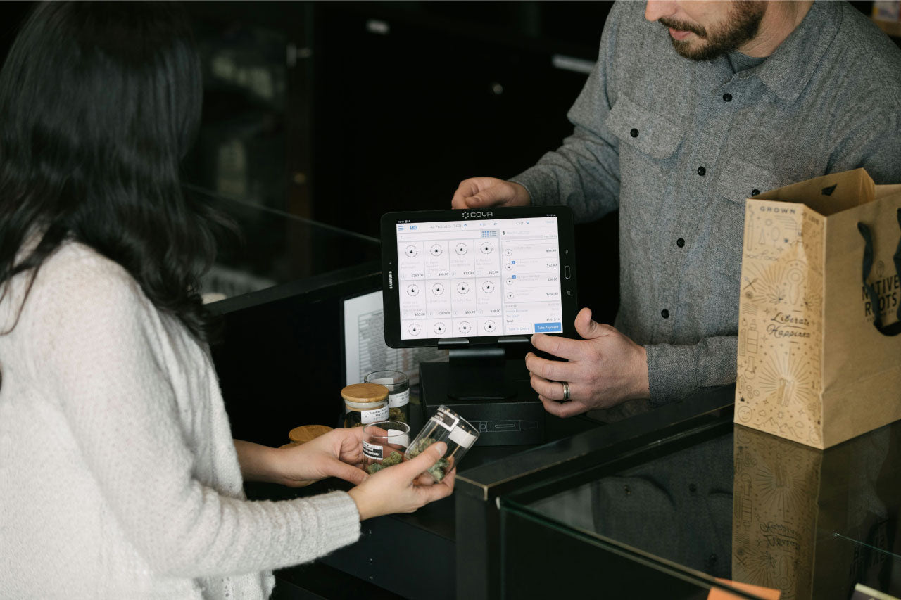 Image of a bud tender in a cannabis dispensary helping a customer.