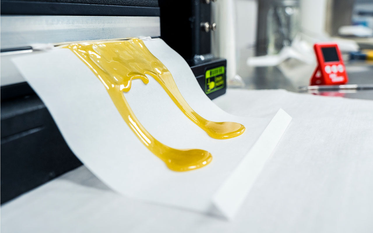 Image of live rosin flowing from a rosin press.