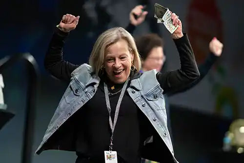 A Retail Success Summit attendee with her hands in the air cheering.