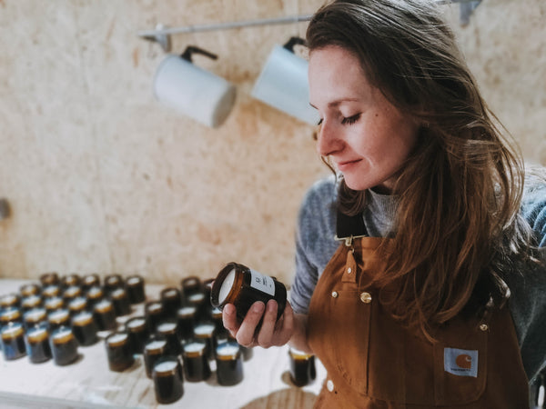 Charley, founder and maker looking at a soy wax candle in her Shropshire studio