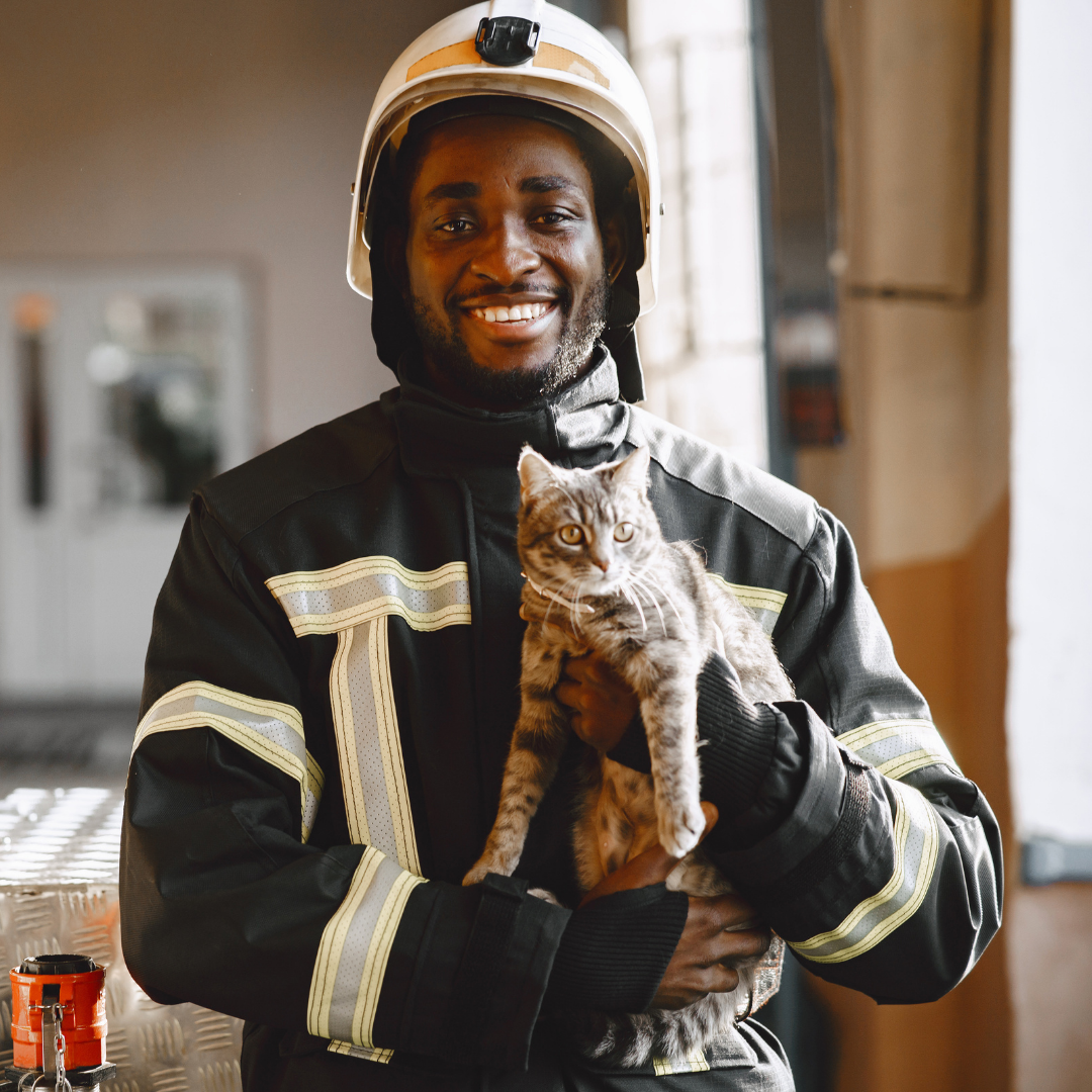 Smiling firefighter holds kitten in hands at the fire station.