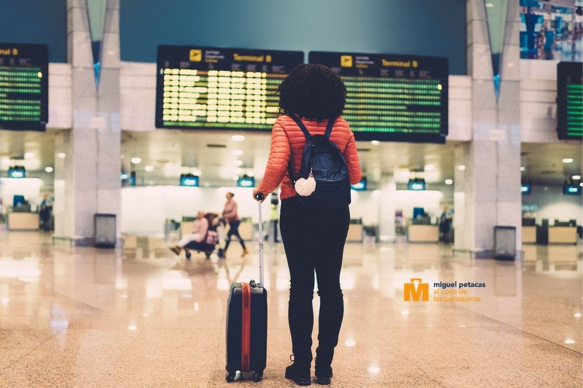 Mujer joven en aeropuerto mirando horarios - Miguel Petacas