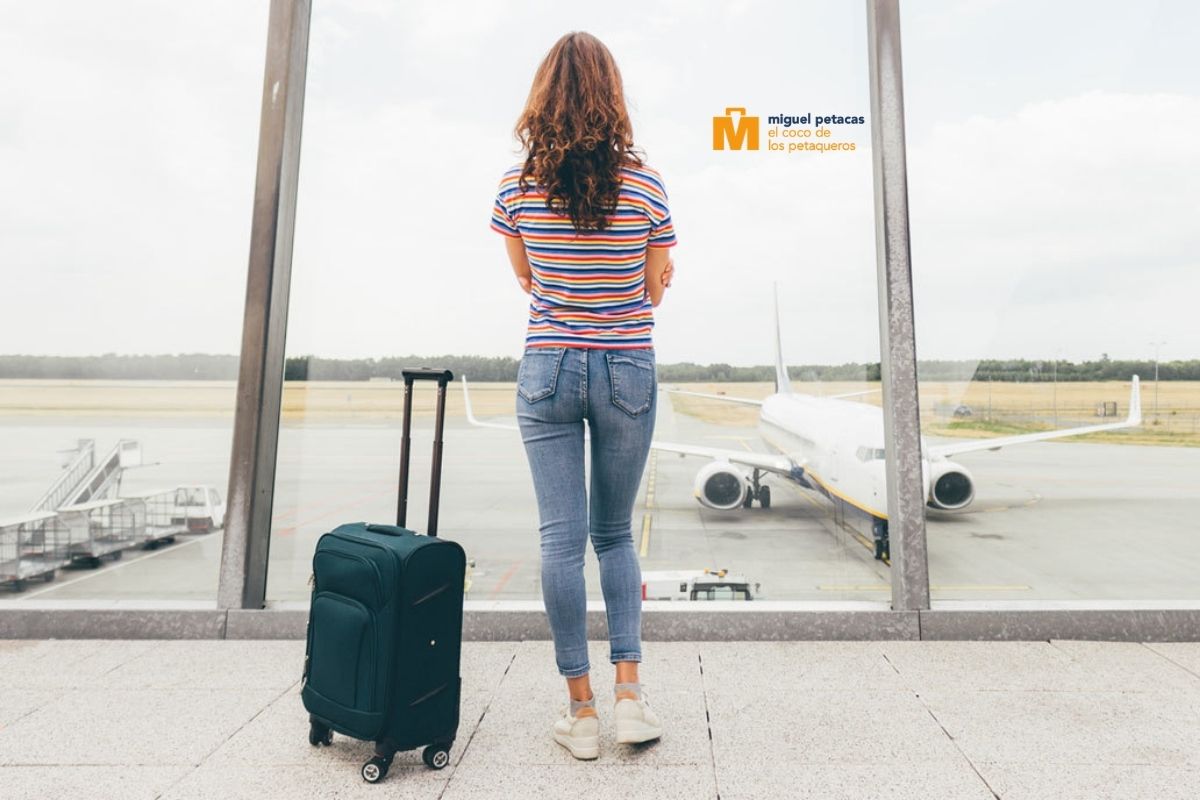 Mujer joven con maleta viendo aeropuerto - Miguel Petacas