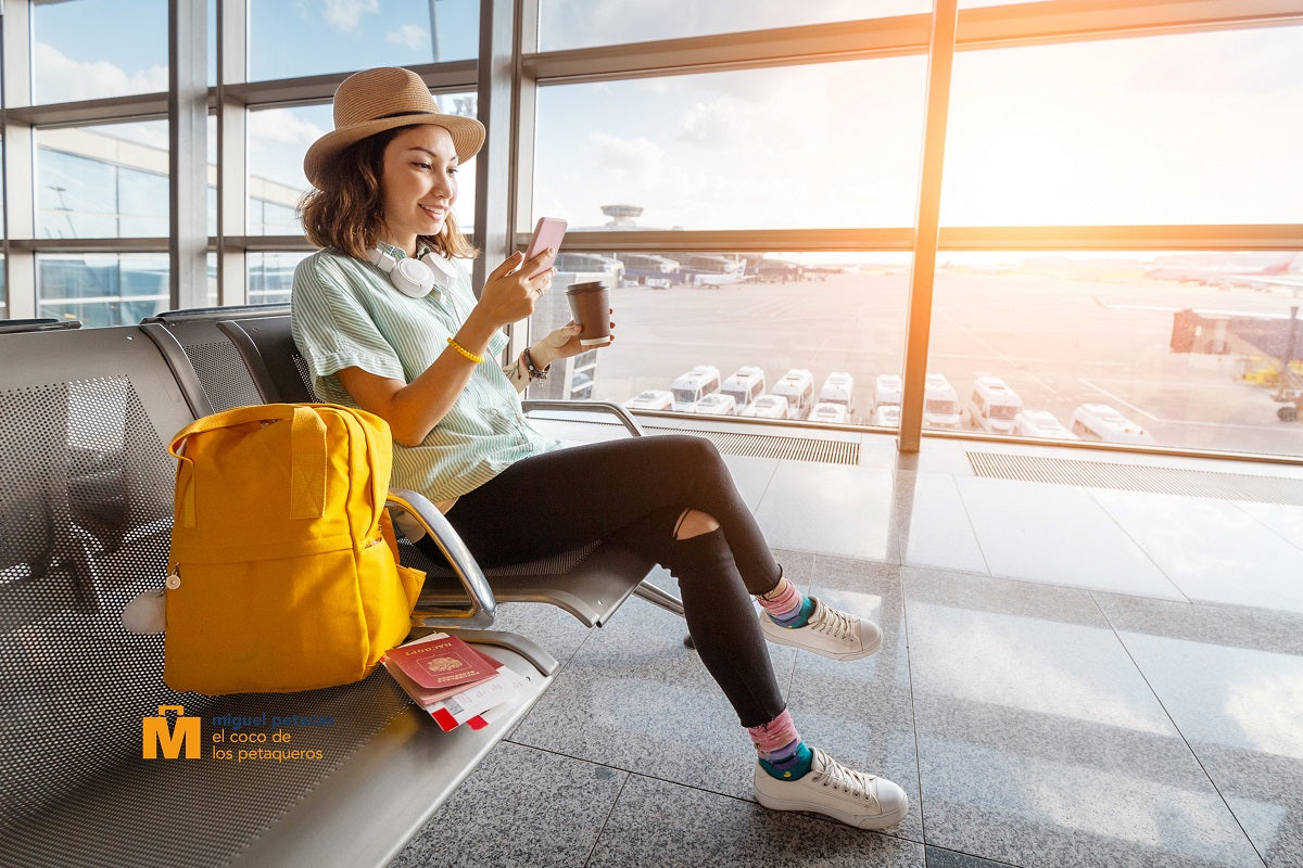 Mujer nómada digital en aeropuerto con mochila y teléfono inteligente: Miguel Petacas