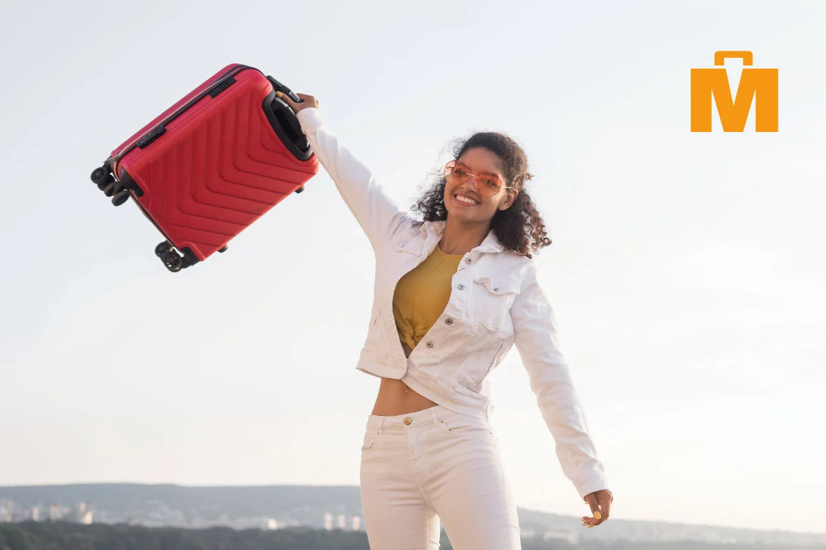 Mujer sosteniendo al aire una maleta de color rojo