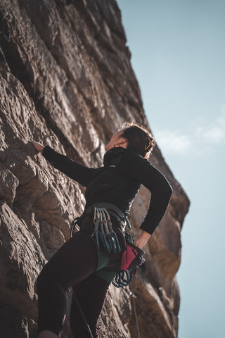 a woman rock climbing in a rock climbing suit