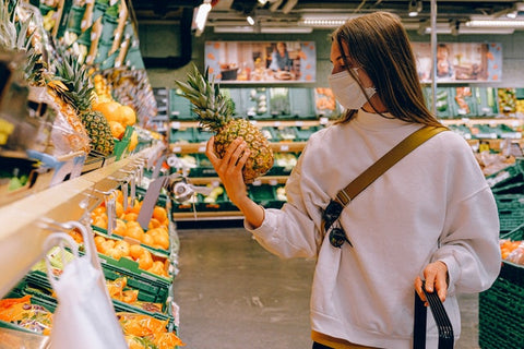 A woman buying healthy fruits in a supermarket with pineapple in her hand