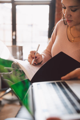 a woman writing something in the notebook