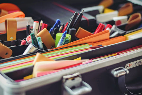 a drawer with organized colorful notepads, post-its, pens, and other office stationary