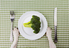 Dog Paws on Table with Plate of Broccoli_