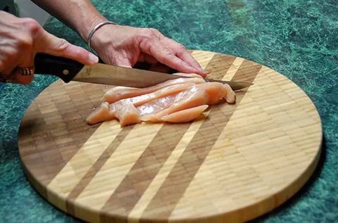 Chicken Strips Being Cut on Chopping Board with a Thin Knife