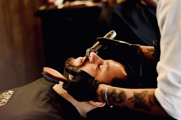 A man at a barbershop getting a beard line up