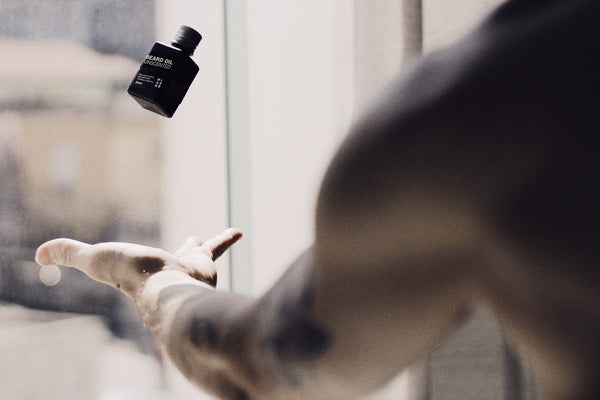 A man tossing beard oil into the air