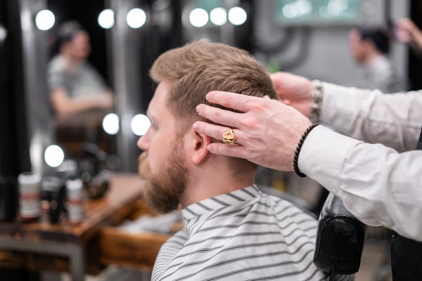 A man getting his beard groomed at a barbershop