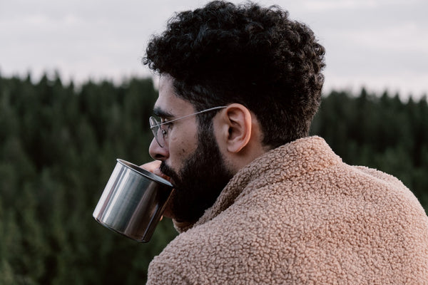 Man in Brown Fur Jacket Holding Stainless Tin Cup