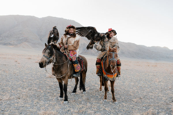 two men in the desert riding horses 