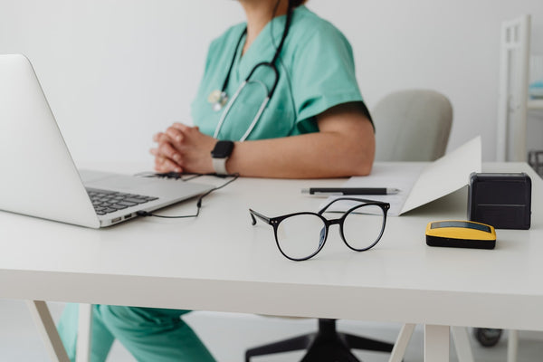 woman in blue scrubs sitting down in an office chair 