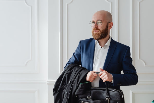 A bald man with a beard carrying a briefcase 