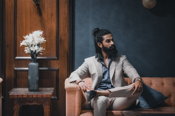 a well dressed bearded man sitting in a chair 