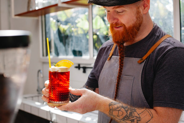 a bearded man pouring up a drink