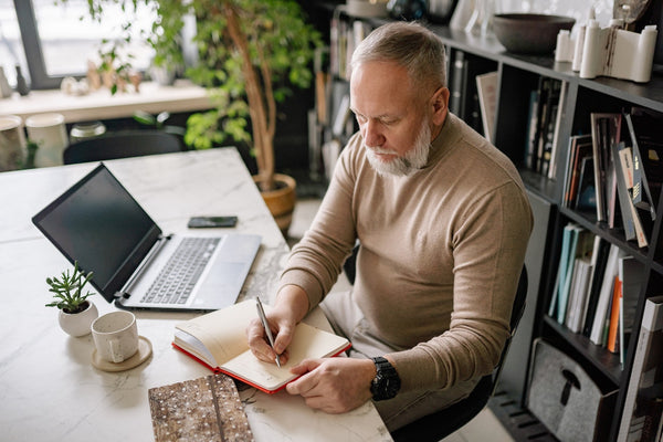 A Man in Brown Sweater Writing in a Diary