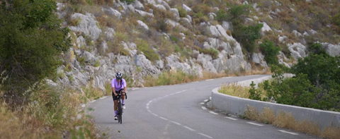 Femme sur son vélo sur une route de montagne